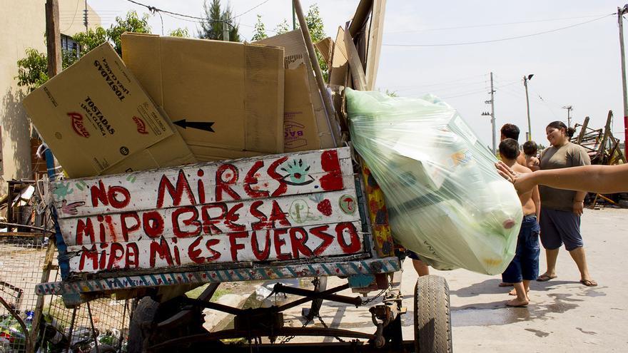 Menores juegan en torno al carro de un recolector de cartón en una calle de Buenos Aires.