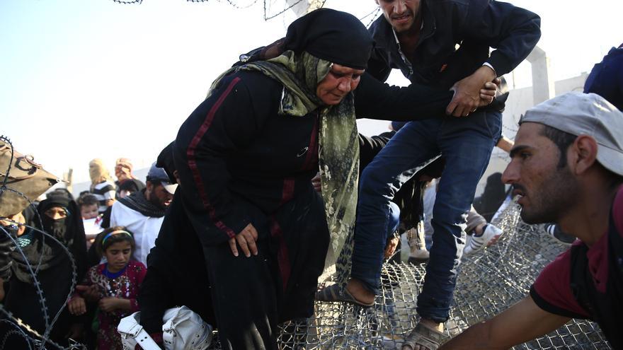 Una mujer mayor siria pasa al lado turco de la frontera ayudada por dos hombres. Cientos de personas se amontonaban en la alambrada pidiendo auxilio a los soldados turcos que tenían la orden de frenar su entrada, aunque finalmente abrieron el paso, según informa EFE. /  (AP Photo/Lefteris Pitarakis)