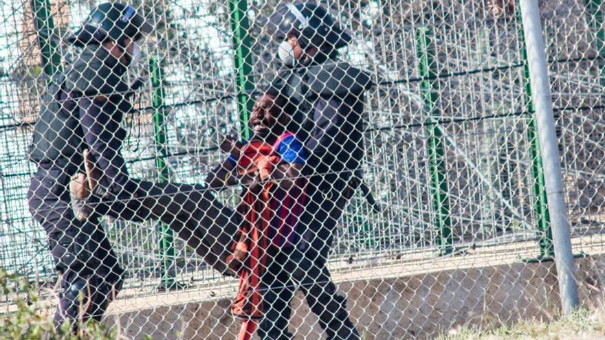 Dos agentes devuelven a un inmigrante a Marruecos tras el intento de salto del 1 de mayo./ Foto:José Palazón.