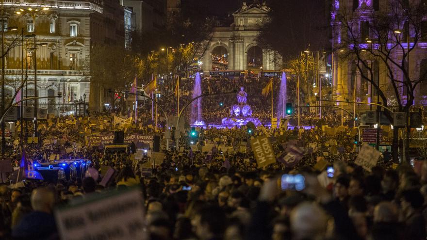 La diosa Cibeles, también iluminada de violeta, y la Puerta de Alcalá, al fondo, muestran una imagen singular entre la riada de manifestantes