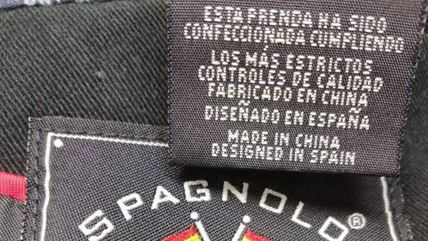 Etiqueta de la marca Spagnolo con dos banderas españolas cruzadas y su lema "Comprometidos con lo nuestro: España".