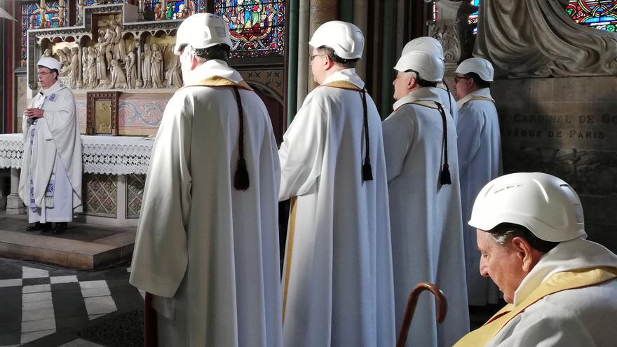 Imagen de los clérigos oficiando con casco la primera misa celebrada en Notre Dame tras el incendio