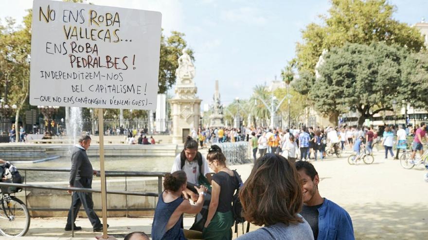 Manifestantes con un cartel que dice: 'No ens roba Vallecas, ens roba Pedralbes'