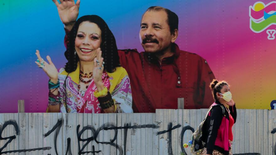 Una mujer con mascarilla camina delante del muro pintado con los rostros del presidente de Nicaragua, Daniel Ortega, y la vicepresidenta, Rosario Murillo, en Managua // REUTERS/Oswaldo Rivas