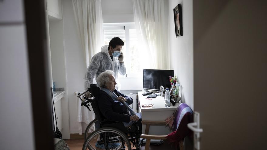 Personal de la residencia para mayores de Pozuelo de Alarcón ayuda a una mujer a comunicarse con sus seres queridos / AP Photo/Bernat Armangue