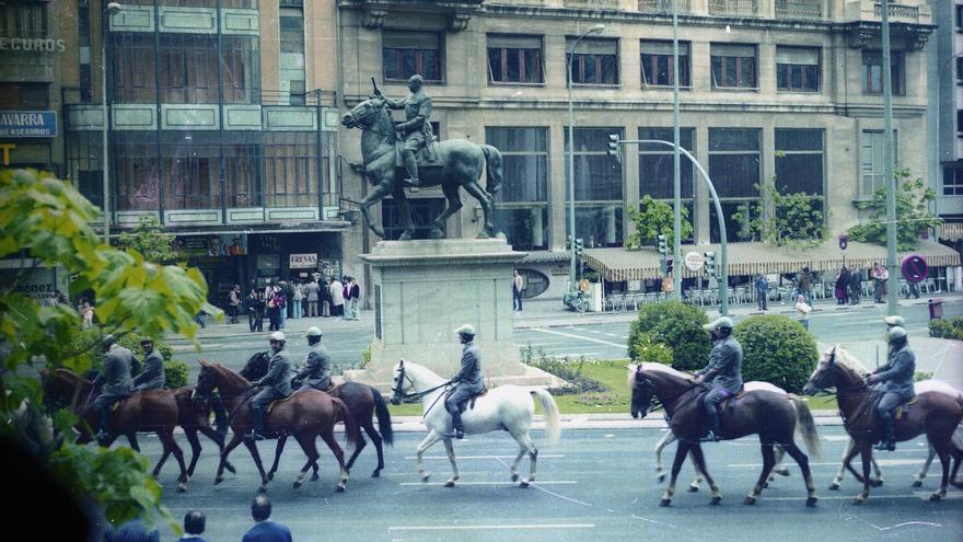 Policía a caballo franquistas patrullan por la Plaza del Ayuntamiento de Valencia frente a la antigua estatua de Franco.