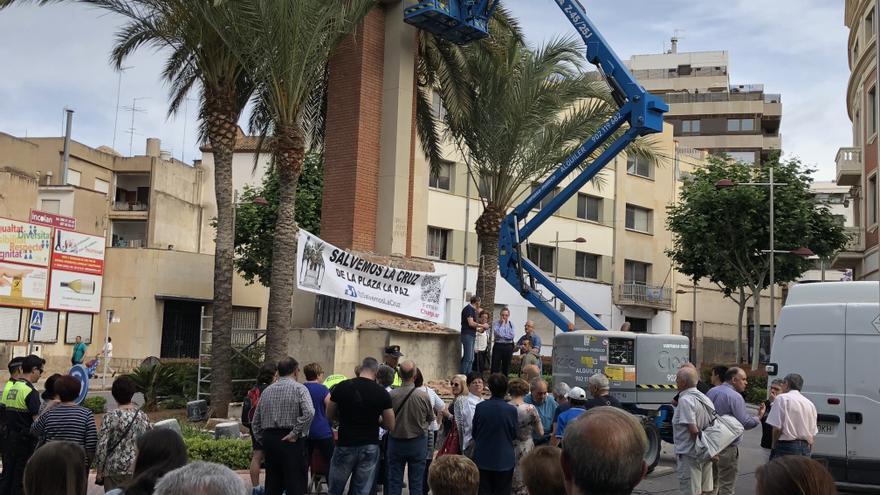 Varios operarios intentan retirar la cruz de los caídos de La Vall d'Uixó (Castelló) en medio de una concentración de protesta. 