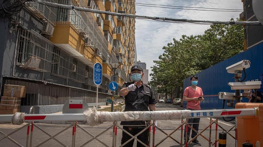 Una persona de seguridad con una mascarilla vigila un complejo residencial cerrado cerca del mercado de Yuquandong, en el distrito de Haidian, Pekín, debido a la propagación de casos de coronavirus.