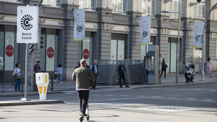 Un hombre en patinete eléctrico por las calles de Madrid al lado de un cartel de Madrid Central