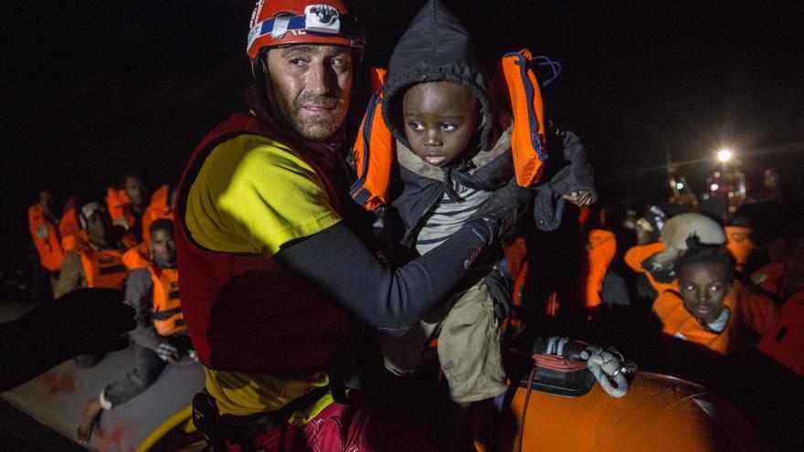 Un miembro de Proactiva Open Arms saca de la barcaza a uno de los niños