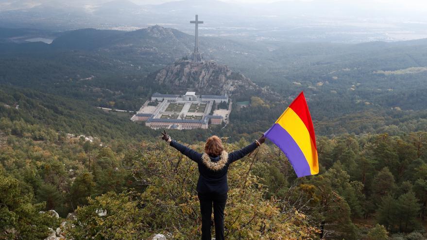 Una mujer ondea la bandera republicana ante el Valle de los Caídos en el día de la exhumación de Franco