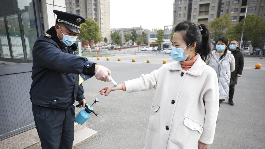 Un trabajador sanitario mide la temperatura a una profesora de una escuela primaria en Jiangsu.